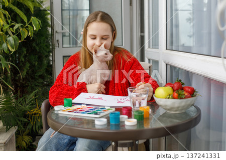 Lovely child girl painting and sitting with cat pet on the terrace. 137241331