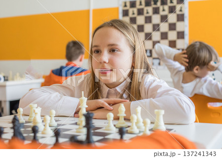 Smart schoolgirl playing chess game in school classroom. Child girl on chess lesson strategy Smart schoolgirl playing chess game in school classroom. Child girl on chess lesson strategy 137241343
