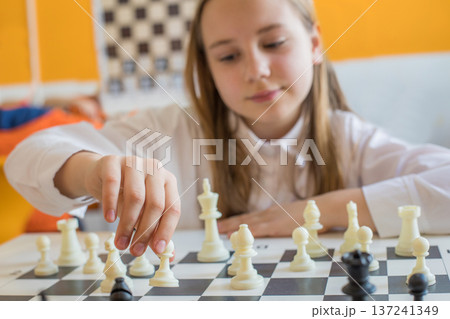 Hand of school girl moving a chess piece on chessboard 137241349