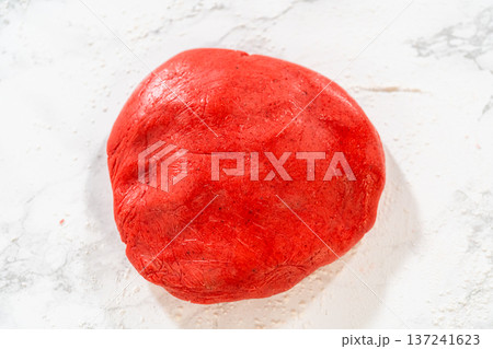 Freshly kneaded Red Gingerbread Cookies dough on a marble surface, vibrant red and ready for rolling. Freshly kneaded Red Gingerbread Cookies dough on a marble surface, vibrant red and ready for rolling. 137241623
