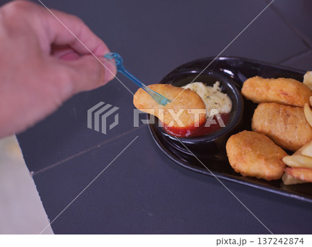 Hand Dipping Crispy Chicken Nugget into Tomato Ketchup 137242874