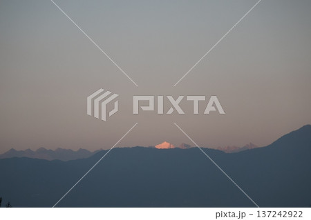 カトマンズのホテルの屋上から見た夕空と光る冠雪のヒマラヤ山脈の山頂とシルエットの近くの山並みの風景 137242922