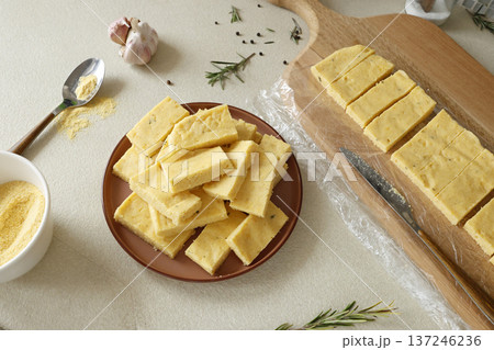 Sliced pieces of hard polenta on table. Cornmeal in kitchen. Ingredients and traditional Italian cuisine. Sliced pieces of hard polenta on table. Cornmeal in kitchen. Ingredients and traditional Italian cuisine. 137246236