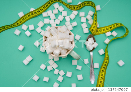 Cup filled with sugar cubes and measuring tape 137247097