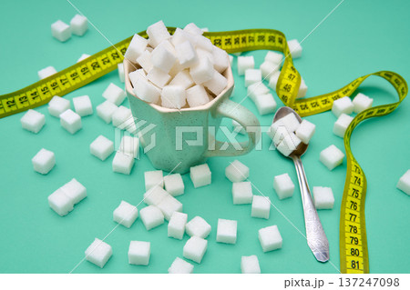 Cup filled with sugar cubes and measuring tape 137247098