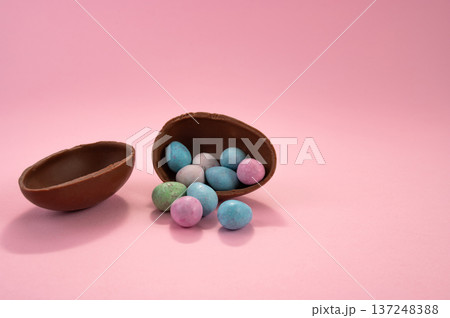 Chocolate Easter eggs and colorful sweets on a pink background. Chocolate Easter eggs and colorful sweets on a pink background. 137248388