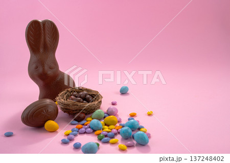 Chocolate Easter eggs and colorful sweets on a pink background. Chocolate Easter eggs and colorful sweets on a pink background. 137248402