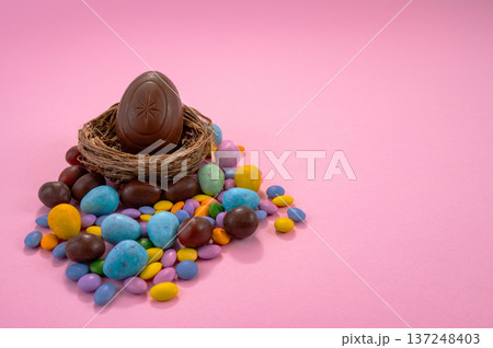 Chocolate Easter eggs and colorful sweets on a pink background. 137248403