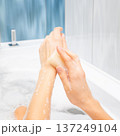 Close up hands of woman washing and forearm with a natural soap bar in a modern bathtub, creating thick white lather and bubbles for gentle skincare, relaxation and personal care routine 137249104