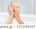 Hands lathering a bar of soap, creating white foam and bubbles over a white ceramic sink, emphasizing personal hygiene, cleanliness, and daily hand washing routine for health and skincare 137249107