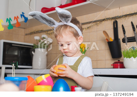 Toddler Painting Easter Eggs at Home in Festive Kitchen Toddler Painting Easter Eggs at Home in Festive Kitchen 137249194