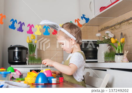 Toddler Painting Easter Eggs at Home in Festive Kitchen 137249202