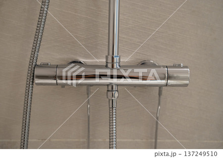 Modern chrome shower mixer faucet in bathroom, providing comfort and hygiene with adjustable water temperature on tiled wall Modern chrome shower mixer faucet in bathroom, providing comfort and hygiene with adjustable water temperature on tiled wall 137249510