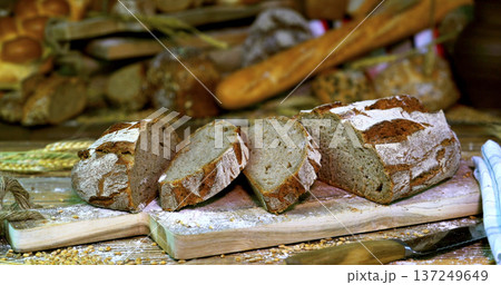 Freshly baked bread on a wooden board with other loaves in a bakery setting during the day 137249649