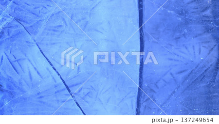 Ice surface shows detailed lines and patterns that reflect light in a blue hue during a cold winter day 137249654