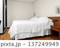Hotel bedroom with white bed, pillows and quilt in neutral interior. Accommodation room with wooden furniture  137249949