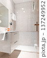 The interior of the hotel bathroom with beige tiled walls, a toilet and a mirror 137249952
