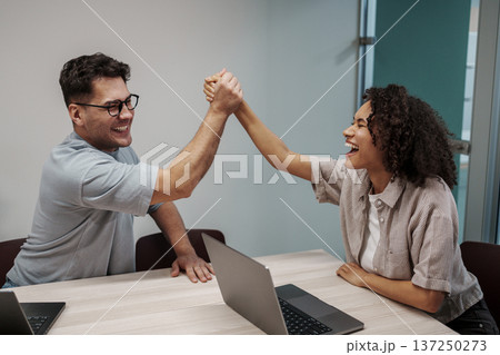 Two Professional Colleagues Exchange Lively Fist Bumps To Commemorate Successful Agreement In Workspace Two Professional Colleagues Exchange Lively Fist Bumps To Commemorate Successful Agreement In Workspace 137250273