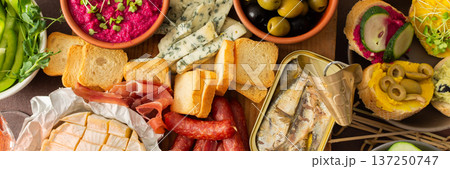 A colorful charcuterie board offers an inviting selection of cheeses, cured meats, fresh bread, nuts, and creamy hummus, perfect for sharing at a casual gathering or picnic, banner A colorful charcuterie board offers an inviting selection of cheeses, cured meats, fresh bread, nuts, and creamy hummus, perfect for sharing at a casual gathering or picnic, banner 137250747