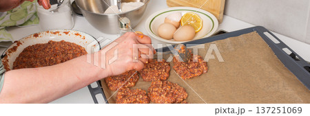 A person prepares liver cutlets in a kitchen located on a balcony. Flowers sit nearby, adding color to the space during the autumn season while cooking begins, banner 137251069