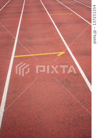 Red running track with white lane lines and directional arrow Red running track with white lane lines and directional arrow 137251354
