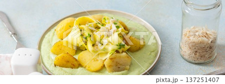 Baked potatoes are topped with slices of fermented zucchini and served alongside a green pea sauce with broccoli. This meal is prepared for a healthy breakfast, banner Baked potatoes are topped with slices of fermented zucchini and served alongside a green pea sauce with broccoli. This meal is prepared for a healthy breakfast, banner 137251407