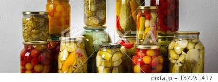 Canning is a common activity in the kitchen as jars filled with vegetables and fruits line the counter. This practice helps in preserving food for winter use and has a long tradition, banner 137251417
