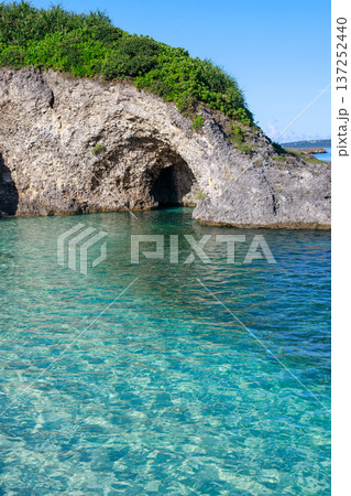 沖縄の岩礁と海食洞、透明な海が広がる南国風景 137252440