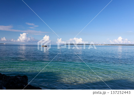 沖縄の透明な海と岩礁、遠くに島影が広がる南国の風景 137252443