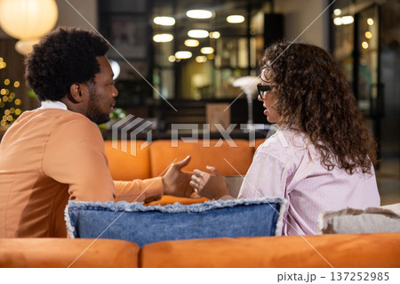 Woman discussing with colleague while sitting on sofa 137252985