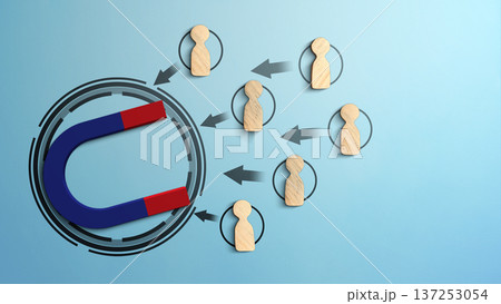 A blue and red horseshoe magnet attracting wooden peg figures representing people or customers. This conceptual image illustrates lead generation, recruitment, and marketing attraction 137253054