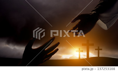 A dramatic silhouette of a hand reaching down from above to meet a hand reaching up, set against a backdrop of three crosses on a hill. Represents faith, salvation, and divine intervention 137253108