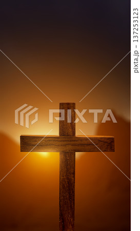 A simple wooden cross stands against a warm, glowing sunset. The soft golden light creates a spiritual and peaceful atmosphere, representing faith, hope, and redemption in Christianity A simple wooden cross stands against a warm, glowing sunset. The soft golden light creates a spiritual and peaceful atmosphere, representing faith, hope, and redemption in Christianity 137253123