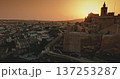 Malta, Comino island: Warm sunset light illuminating the Cittadella bastions in Gozo, Malta, blending history with a modern urban landscape. Drone flight over evening city Malta, Comino island: Warm sunset light illuminating the Cittadella bastions in Gozo, Malta, blending history with a modern urban landscape. Drone flight over evening city 137253287