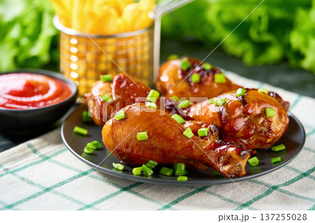 Grilled chicken drumsticks with ketchup and french fry on a black table. Grilled chicken drumsticks with ketchup and french fry on a black table. 137255028