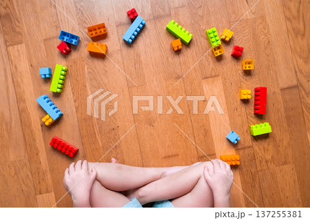 Child playing with colorful building blocks on wooden floor 137255381