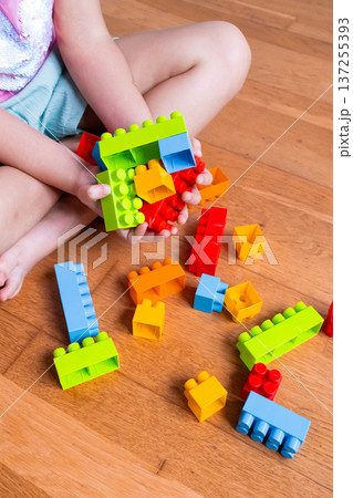 Child building colorful blocks on wooden floor Child building colorful blocks on wooden floor 137255393