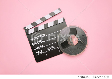 Movie clapper with film reel on pink background Movie clapper with film reel on pink background 137255486
