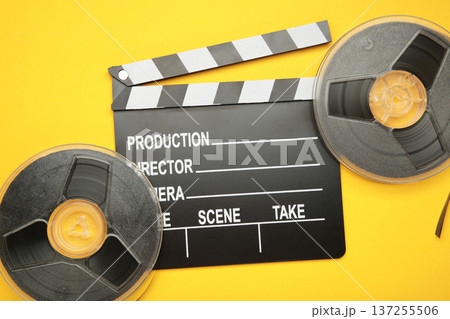 Movie clapper with popcorn and film reels on yellow background 137255506