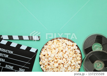 Movie clapper with popcorn and film reels on mint background Movie clapper with popcorn and film reels on mint background 137255509