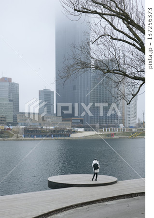 Solitary woman gazing at the urban waterfront from the platform Solitary woman gazing at the urban waterfront from the platform 137256373