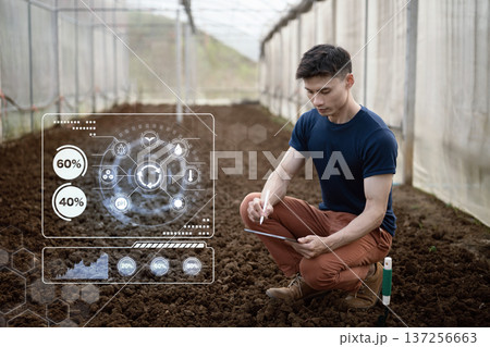 Farmer analyzes soil conditions in greenhouse using tablet and digital data interface to monitor nutrients moisture and crop readiness. Farmer analyzes soil conditions in greenhouse using tablet and digital data interface to monitor nutrients moisture and crop readiness. 137256663