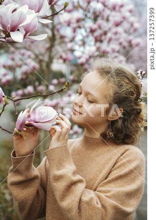 Girl Appreciating Blossoming Magnolia in Springtime Girl Appreciating Blossoming Magnolia in Springtime 137257399