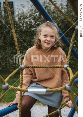 Smiling Child Sitting on Playground Rope Structure 137257519
