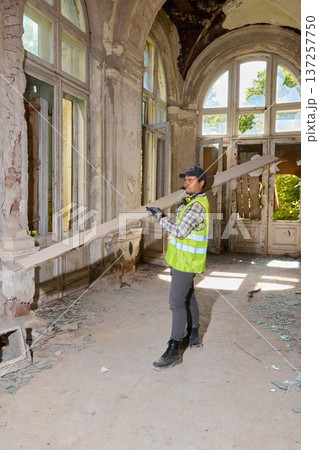 Individual carrying wooden beam in bright colonial mansion corridor Individual carrying wooden beam in bright colonial mansion corridor 137257750