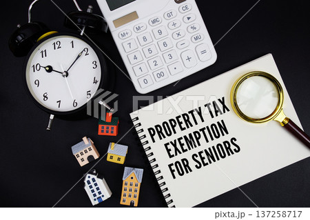 Notepad with the phrase "Property Tax Exemption For Seniors" surrounded by a pen, calculator, magnifying glass, clock, and house model Notepad with the phrase "Property Tax Exemption For Seniors" surrounded by a pen, calculator, magnifying glass, clock, and house model 137258717