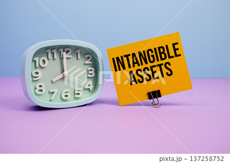 Intangible Assets text and alarm clock on blue and purple background Intangible Assets text and alarm clock on blue and purple background 137258752