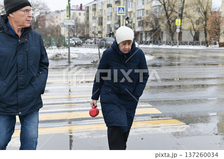 Friends share hot drinks from thermos while standing on snowy wooden deck 137260034