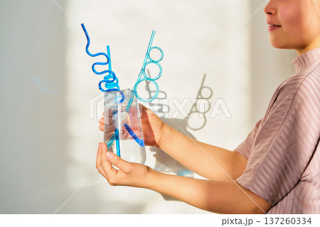 Child holding glass with water and creative straws Child holding glass with water and creative straws 137260334