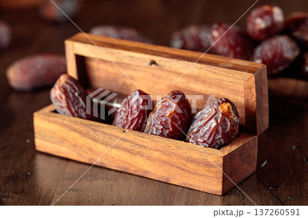 Dates fruits in small wooden box on an old wooden table. 137260591